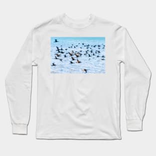 Flight of cormorant blurred in motion in flight over blue water Long Sleeve T-Shirt